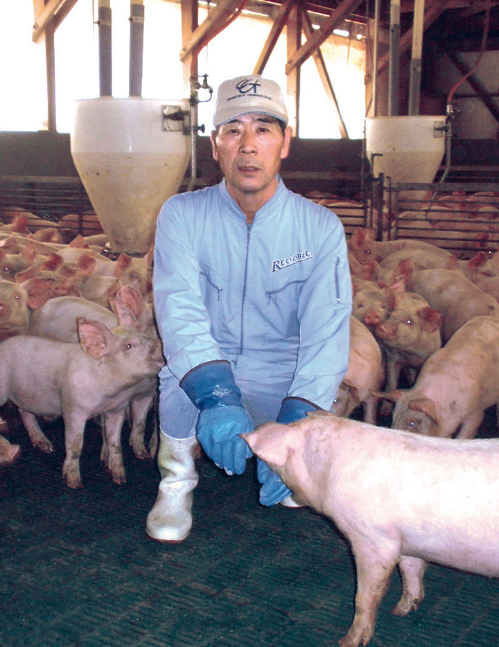 柿崎義美さんと飼育している豚の写真